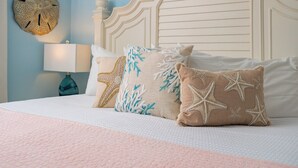Een bed met wit beddengoed, een decoratief hoofdbord en kussens met een sterrenbeelden-motief.