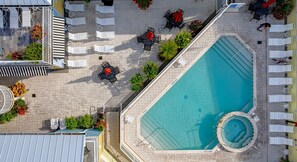Eine Vogelperspektive eines Hotels mit Schwimmbad, Liegestühlen und Außenbereichen zum Sitzen.