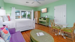 A bedroom with a bed, a small table, a chair, a wardrobe, and a door. - Harbour House #310 "Sandpiper Retreat" (Fort Myers Beach)