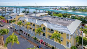 Um hotel de vários andares com telhado plano, situado perto de uma marina com barcos e uma ponte.