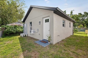 Un bâtiment d’un seul étage, à l’extérieur blanc, avec une porte d’entrée et un petit porche.