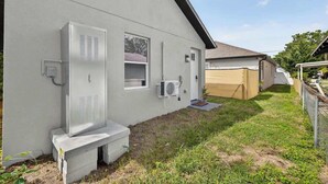 En bostadsbyggnad med en grå fasad, en vit dörr och ett litet fönster.