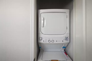 En liten, vit tvättmaskin placerad på en liten yta, troligen i ett förråd eller tvättstuga.