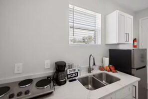 A modern kitchen with a coffee maker, a sink, and a refrigerator. - Brand-New 1BR • Minutes to Tampa’s Top Attractions (Tampa)