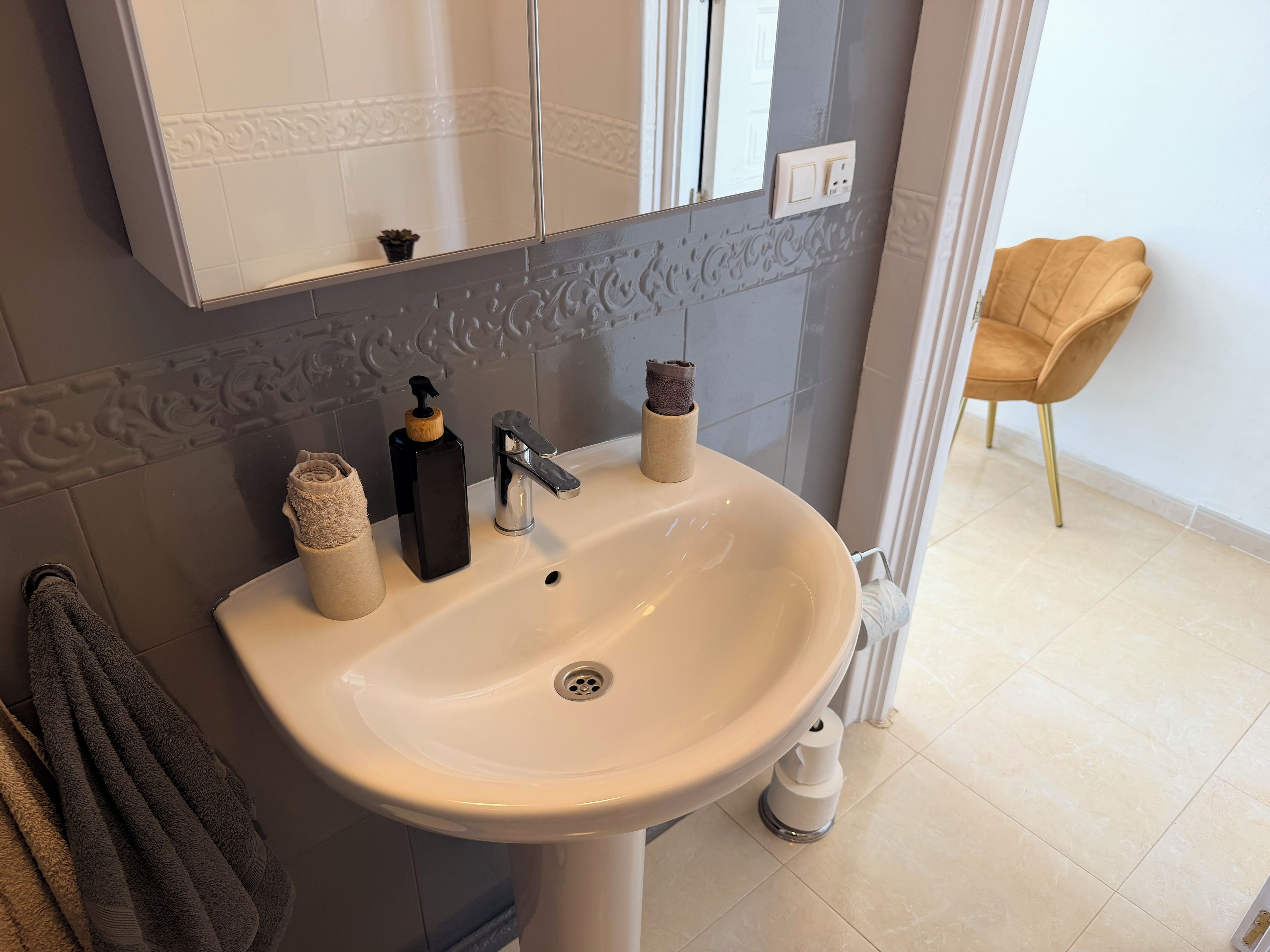 A bathroom with a white sink, a mirror above it, and a towel rack with towels.