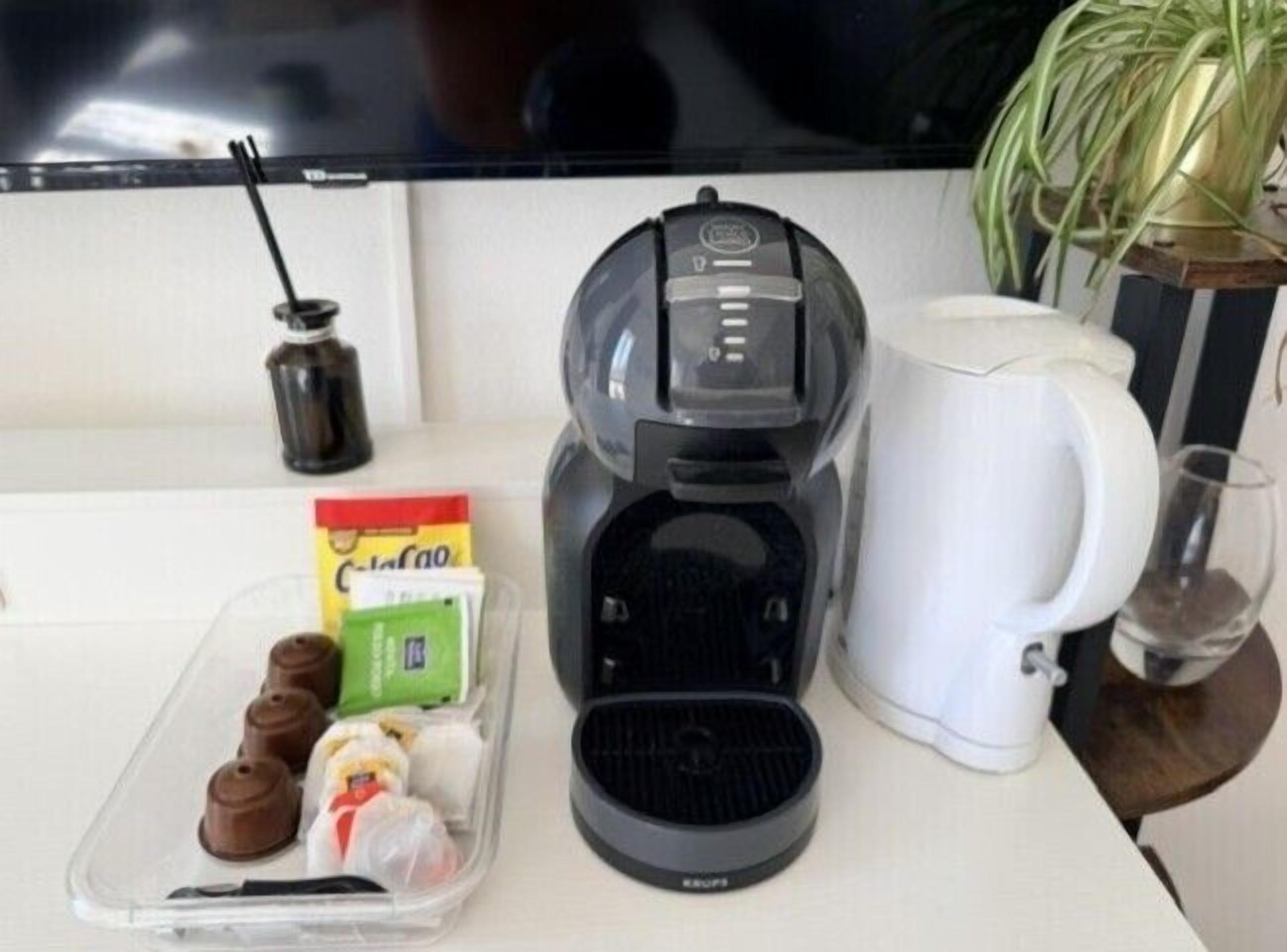 A kitchen counter with a coffee maker, a white mug, and a container of snacks.