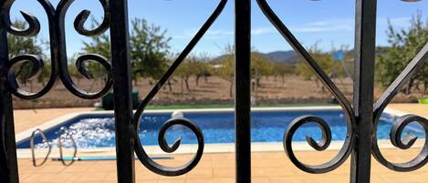 A pool area with a view of a mountainous landscape, surrounded by a metal fence with decorative elements.