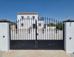 A gated entrance with a white building in the background.