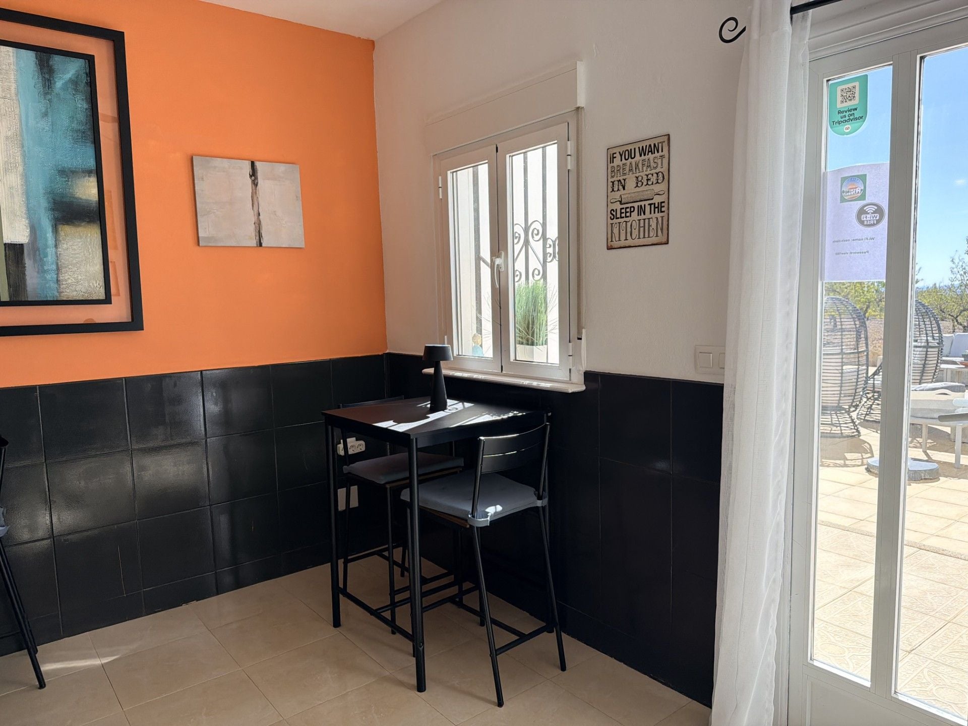 A small dining area with a table and chairs, a window with a view, and a sign on the wall.