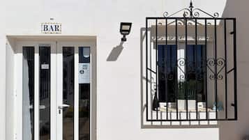 Un bâtiment avec une enseigne de bar, une caméra de surveillance et un portail en fer forgé décoratif.