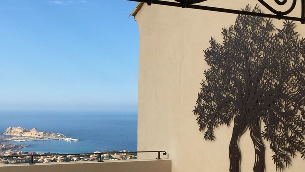 Un balcon doté d’une balustrade en métal, d’un fauteuil de relaxation et d’une fresque murale représentant un arbre.