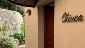 Une entrée d’immeuble avec un mur en pierre, une porte en bois et une plaque portant le nom « Olivea ».