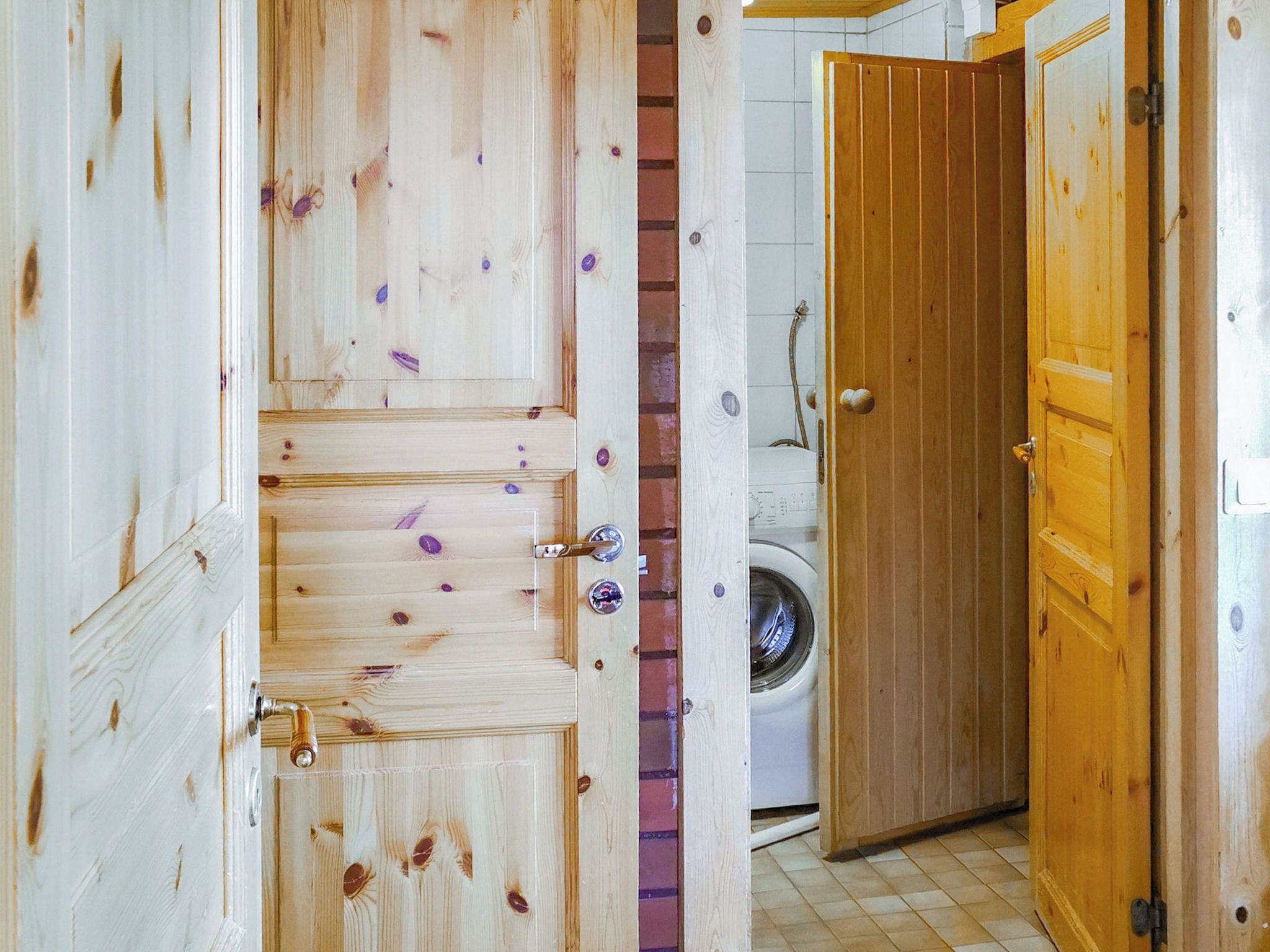 A wooden door with a metal handle, a washing machine, and a tiled floor.