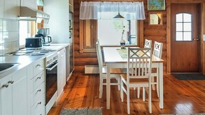 A wooden cabin interior with a kitchen, dining area, and a door. - Sinikello by Interhome (Pertunmaa)