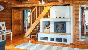 A wooden interior with a fireplace, a staircase, and a dining area. - Sinikello by Interhome (Pertunmaa)