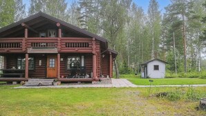 A log cabin with a porch, a small adjacent shed, and a grassy area in front. - Sinikello by Interhome (Pertunmaa)