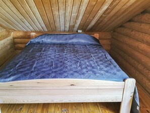 Een klein houten huisje met een enkel bed, voorzien van een blauw beddegoed met patroon.