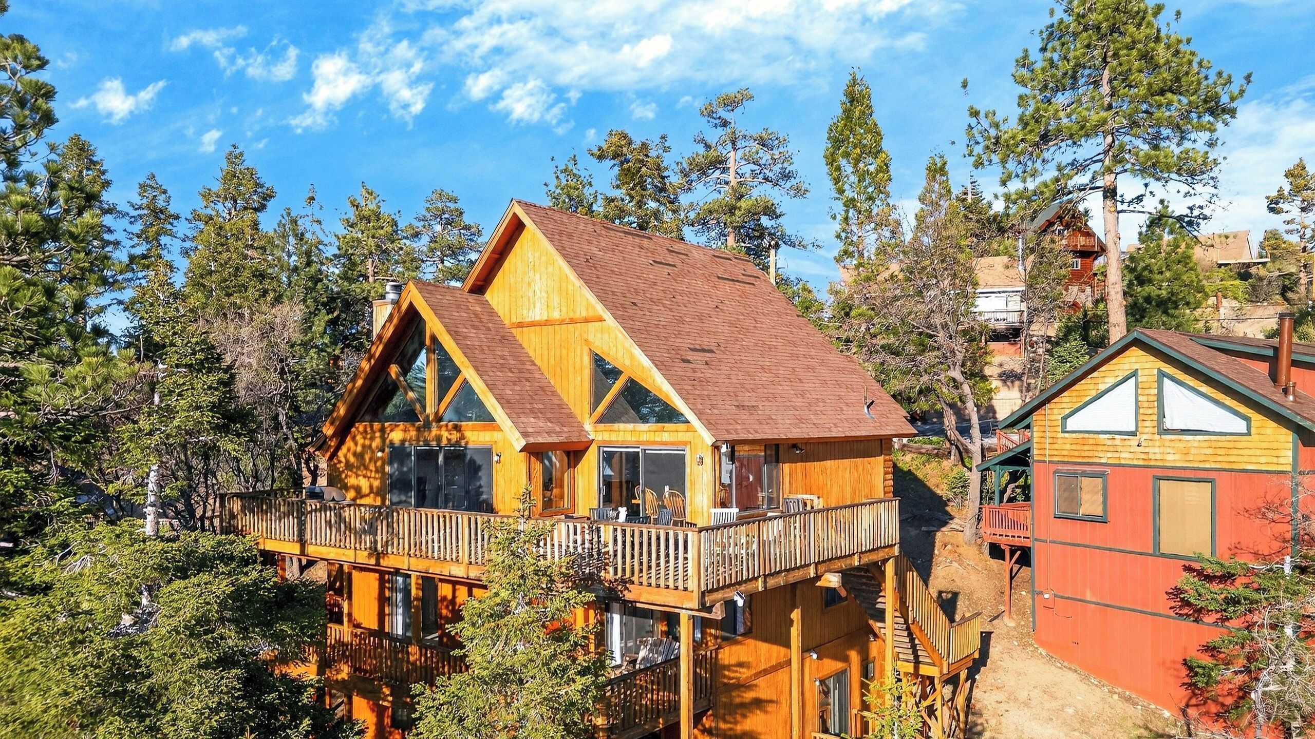 A wooden cabin with a balcony, surrounded by trees.