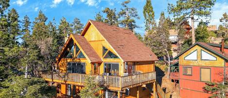 A wooden cabin with a balcony, surrounded by trees.