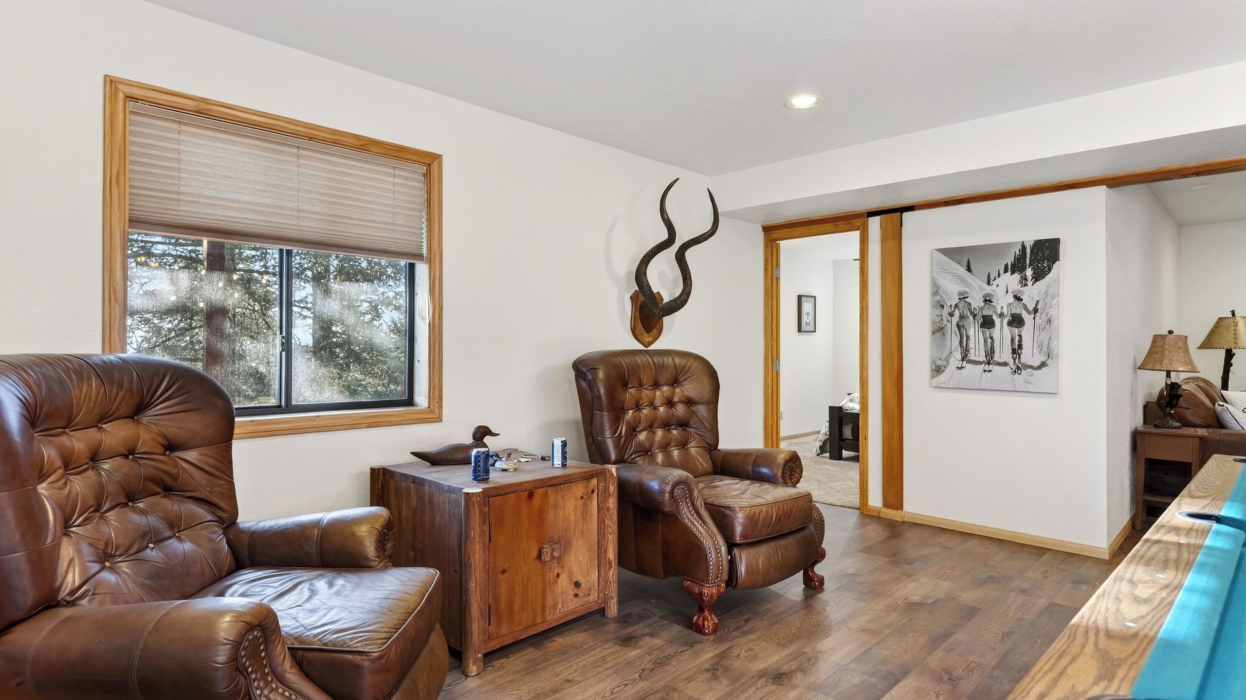 A spacious living room with leather sofas, a wooden coffee table, and a large window with blinds.