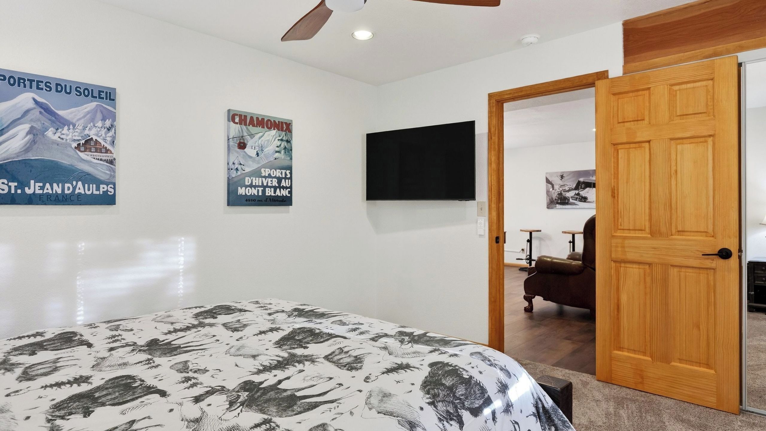 Ein Schlafzimmer mit einem Bett, Postern an der Wand, einem Fernseher und einer Holztür.