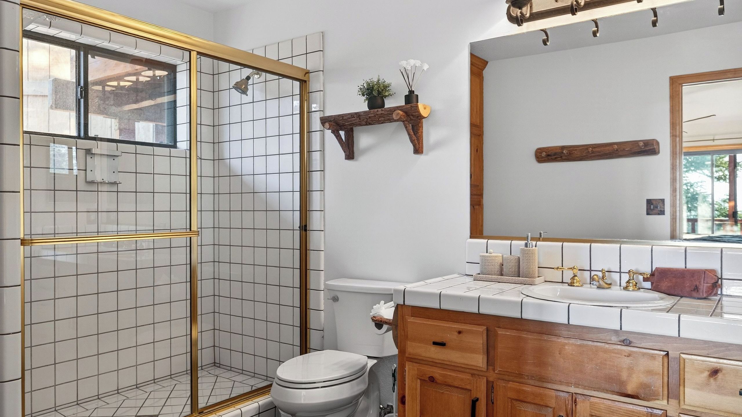 A bathroom with a shower, toilet, sink, and wooden cabinets.