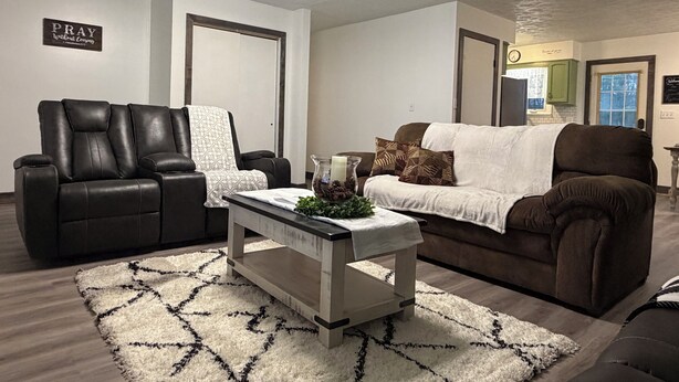 A living room with a black leather sofa, a white sofa, a coffee table, and a patterned rug. - 3-bedroom house in Shiloh ,enjoy a peaceful stay in the country. (Shiloh)