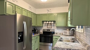 A kitchen with green cabinets, stainless steel appliances, a microwave, and a sink. - 3-bedroom house in Shiloh ,enjoy a peaceful stay in the country. (Shiloh)