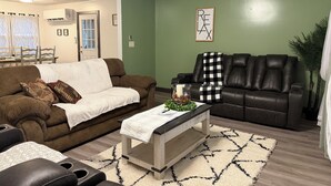A living room with a brown couch, a black leather sofa, and a coffee table with a white cloth. - 3-bedroom house in Shiloh ,enjoy a peaceful stay in the country. (Shiloh)