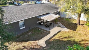 Ein zweistöckiges Haus mit überdachter Terrasse, einem kleinen Vorgarten und einem Baum.