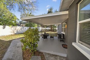 A covered patio with outdoor furniture, a small plant, and a white fence. - Beautiful 4/2 house, minutes from Busch Gardens (Tampa)
