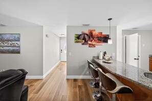 A modern kitchen with a bar area, wooden flooring, and a large painting on the wall. - Beautiful 4/2 house, minutes from Busch Gardens (Tampa)