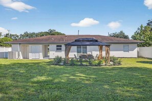 Ein Bungalow mit überdachter Terrasse, Rasenfläche und blauem Himmel.
