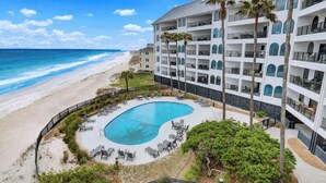 Un hotel con piscina, vistas a la playa y varios balcones.