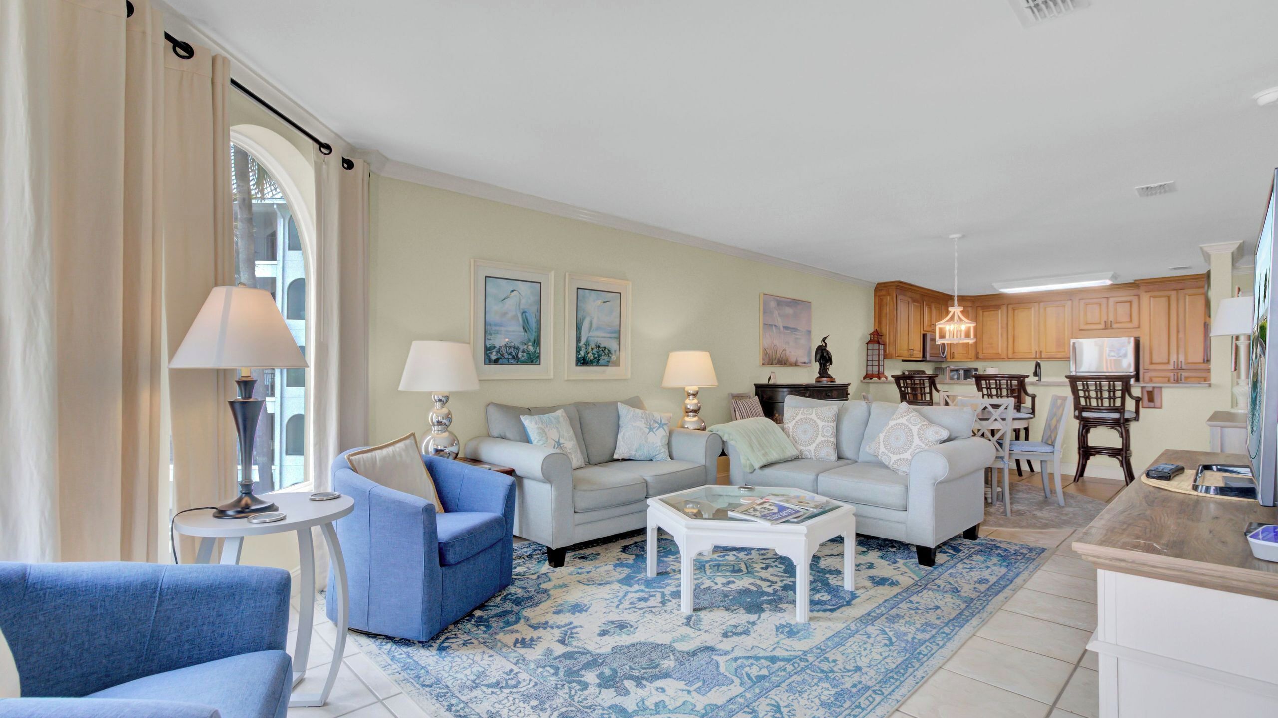 A living room with two sofas, a coffee table, and a dining area with wooden cabinets and chairs.