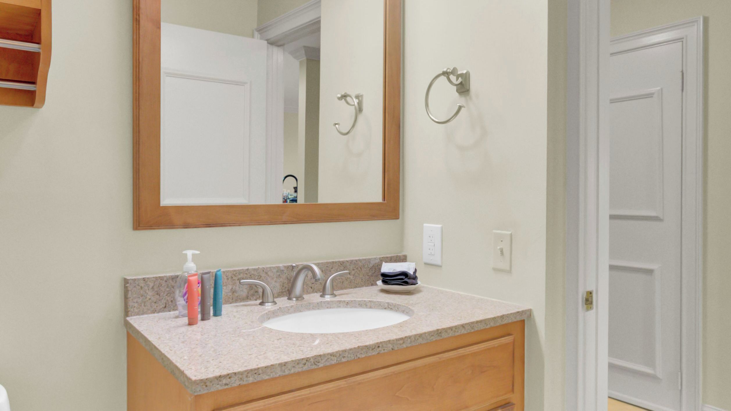 A bathroom with a sink, mirror, and towel ring.