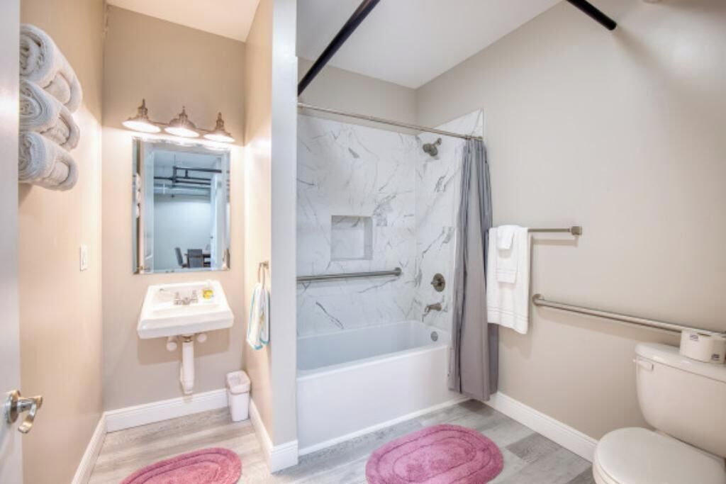 A bathroom with a sink, mirror, shower, and toilet.