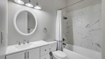 A bathroom with a white sink, round mirror, and a shower curtain.