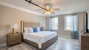 A bedroom with a bed, nightstands, a ceiling fan, and a dresser. - 902 Howard Lofts (Biloxi)
