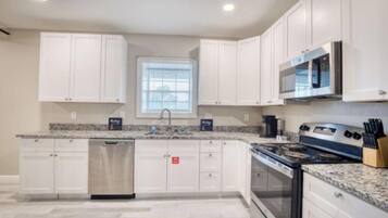 A kitchen with white cabinets, a stainless steel stove, a microwave, and a dishwasher.