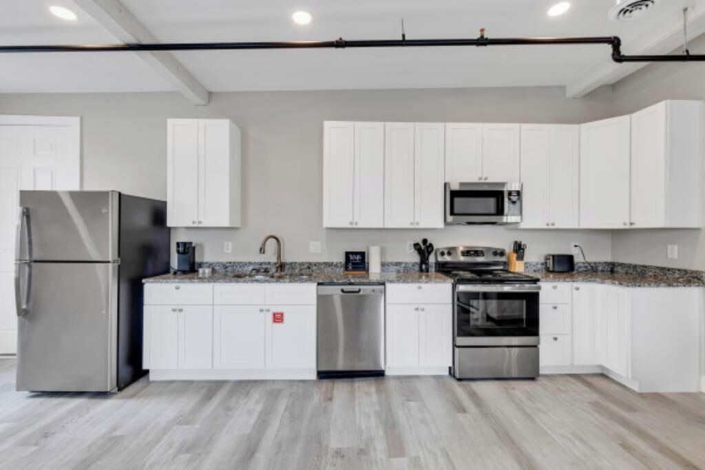 A modern kitchen with white cabinets, stainless steel appliances, and a granite countertop.