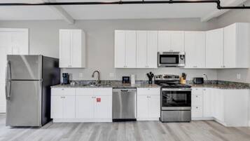 A modern kitchen with white cabinets, stainless steel appliances, and a granite countertop.