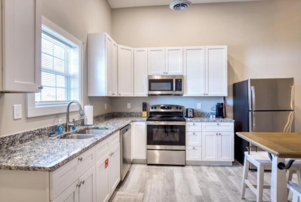 A kitchen with white cabinets, a stainless steel oven, a microwave, and a refrigerator.