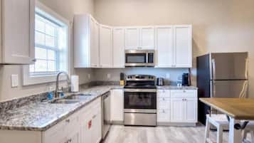 A kitchen with white cabinets, a stainless steel oven, a microwave, and a refrigerator.
