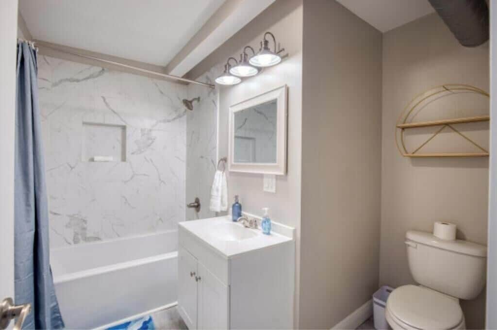 Une salle de bain avec une baignoire, un lavabo avec un miroir, des toilettes et un porte-serviettes.