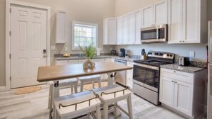 A kitchen with white cabinets, a wooden island, stainless steel appliances, and a window. - 902 Howard Lofts (Biloxi)