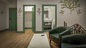 A room with a wooden floor, a white marble coffee table, green upholstered chairs, and a bed with a metal headboard. - Hotel Mojo (Ocean Springs)