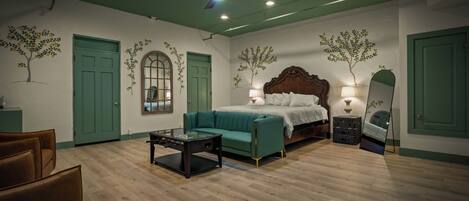 A room with a bed, a sofa, a coffee table, a ceiling fan, and a mirror.
