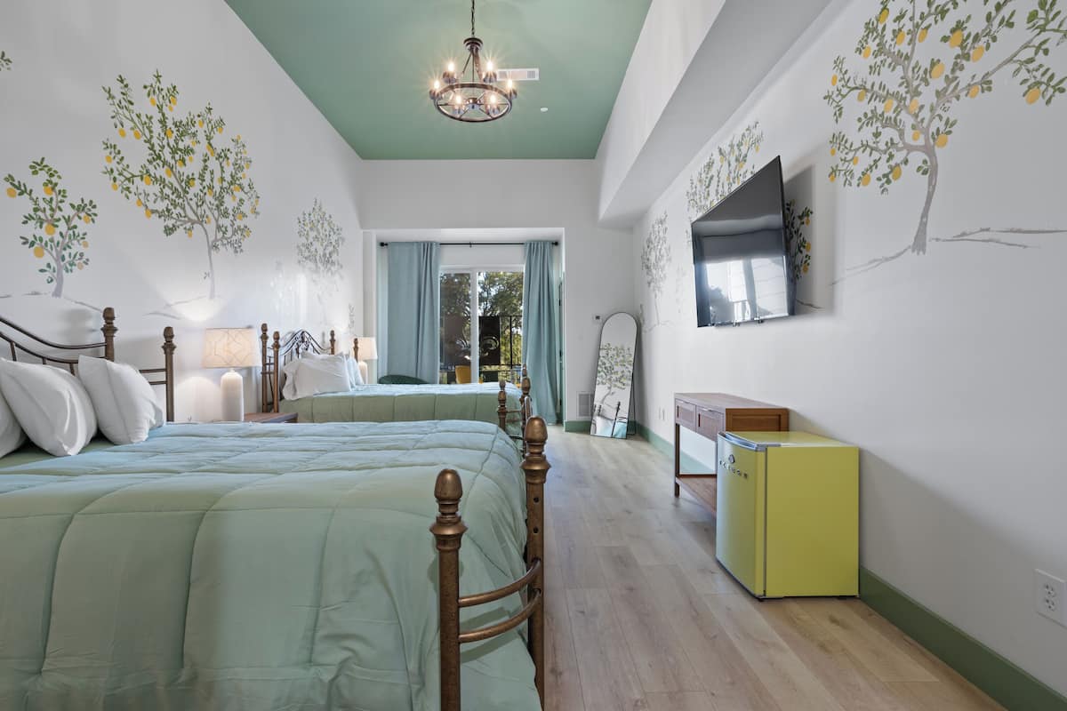 Ein Schlafzimmer mit zwei Betten, einer Holzkommode, einem Fernseher und einer Deckenleuchte.