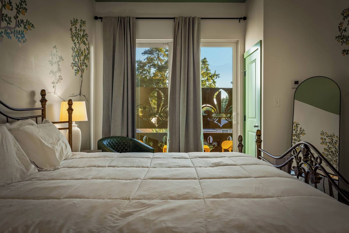 Ein Schlafzimmer mit Bett, Stuhl, Lampe und Blick ins Freie.